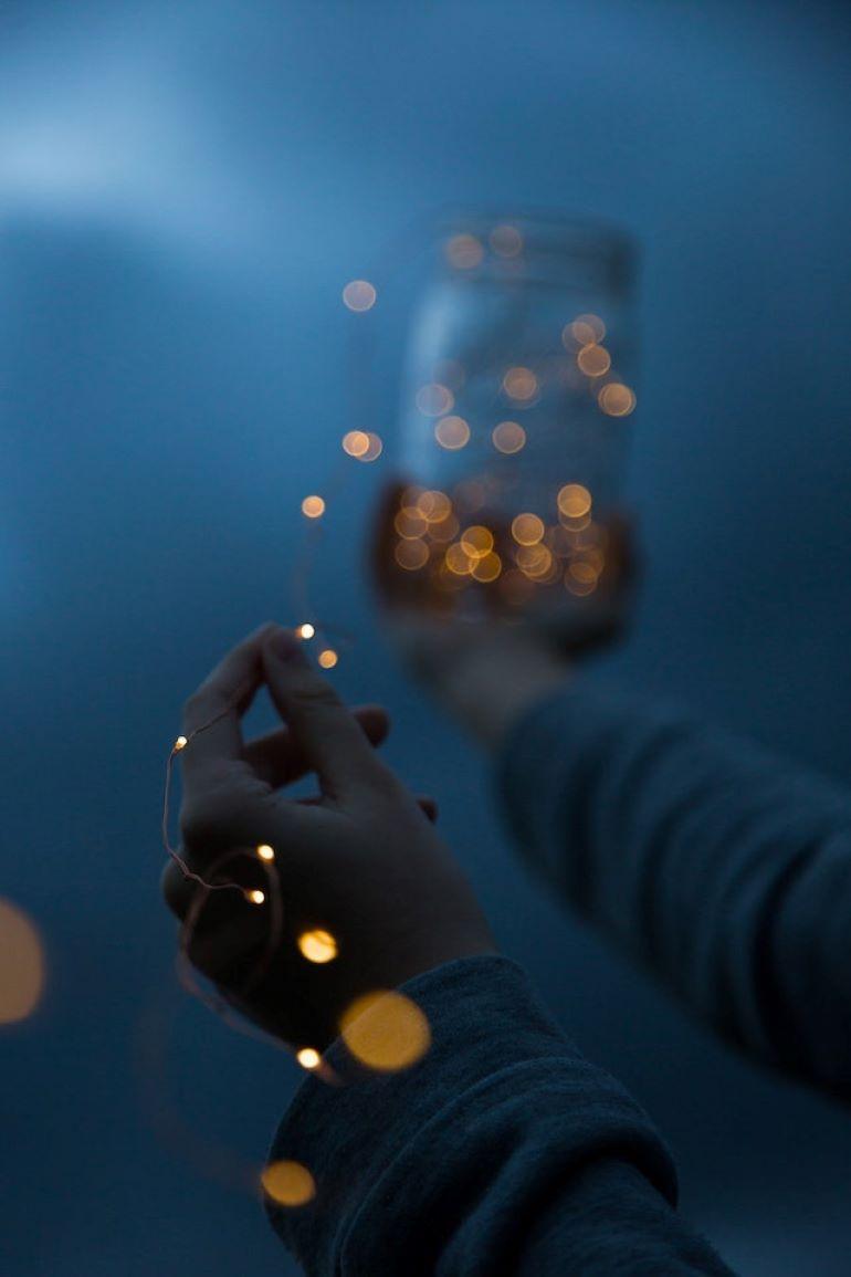 A person is holding a jar full of light strings.
