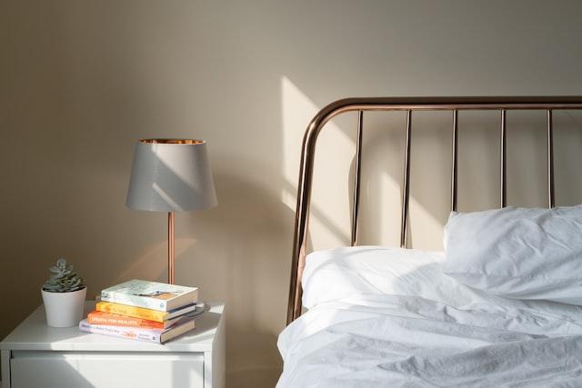 Bedside lamp on a table with books and a plant